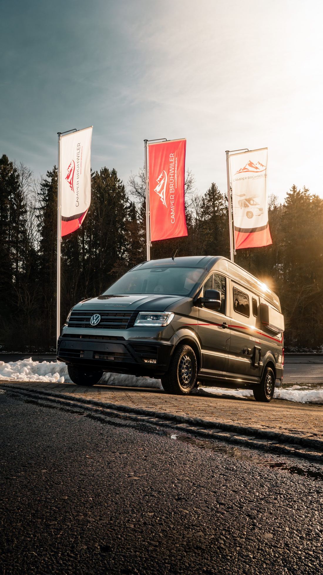 Camper-Brühwiler-Beachflags und Dethleffs Globetrail vor winterlicher Kulisse